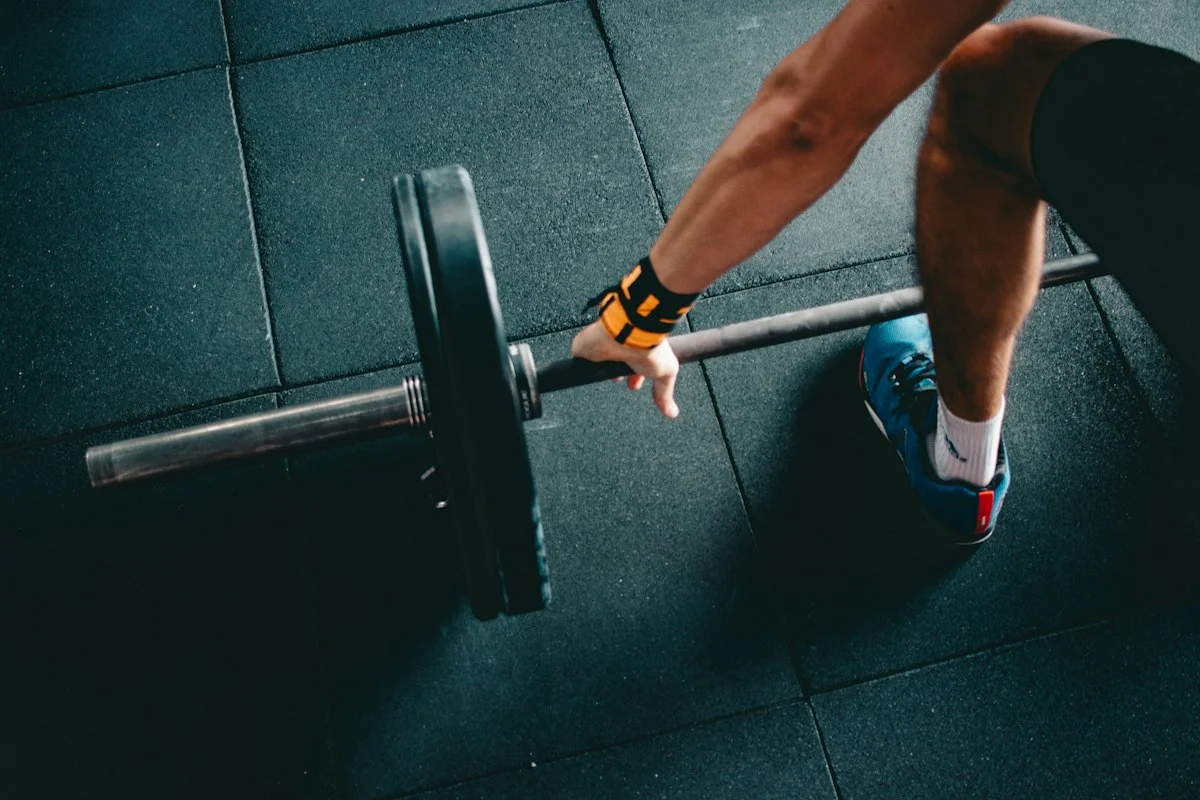 Athlete performing resistance training wearing smart wireless pneumatic blood flow restriction cuffs on upper arms