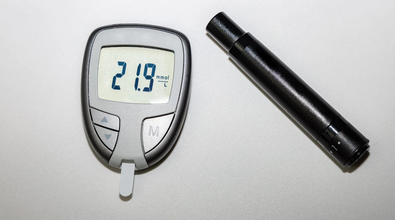 Metabolic health analysis showing a continuous glucose monitor sensor applied to an arm alongside a traditional fingerstick glucometer