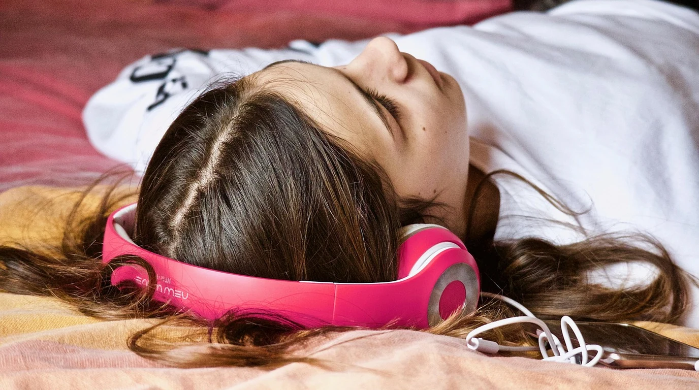 Bedside sleep sound masking speaker emitting calibrated pink noise next to active noise cancelling earbuds